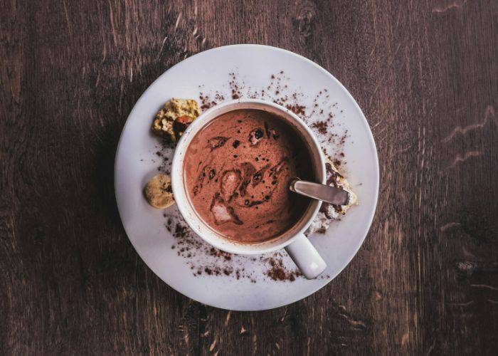 A top-down shot of a hot chocolate, with a sprinkling of cocoa powder around the mug.